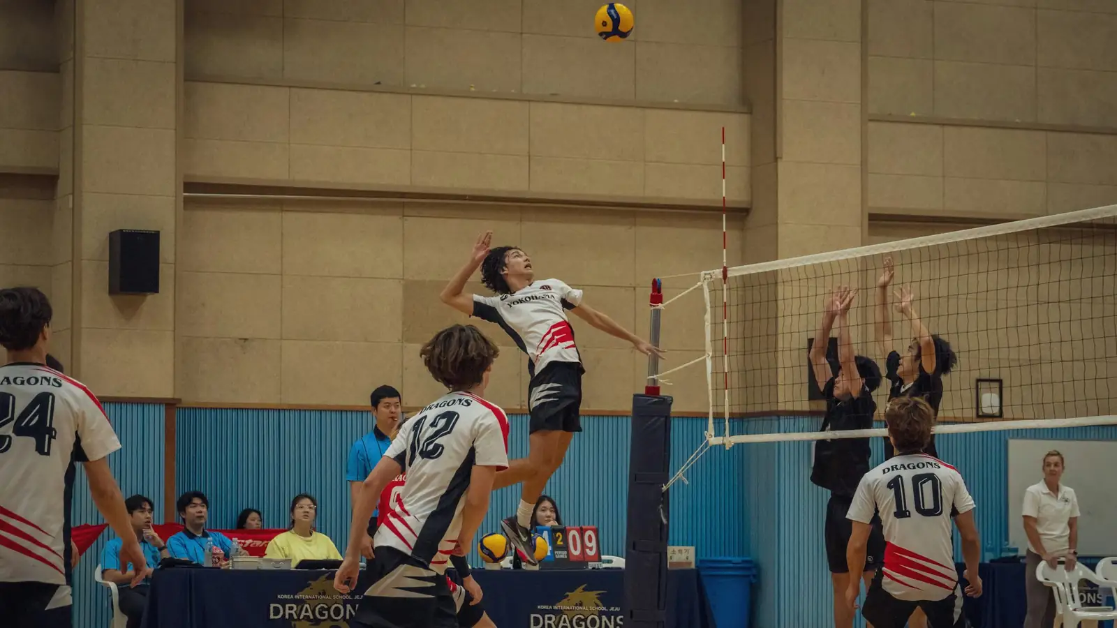 Volleyball player spiking in mid-air against a double block