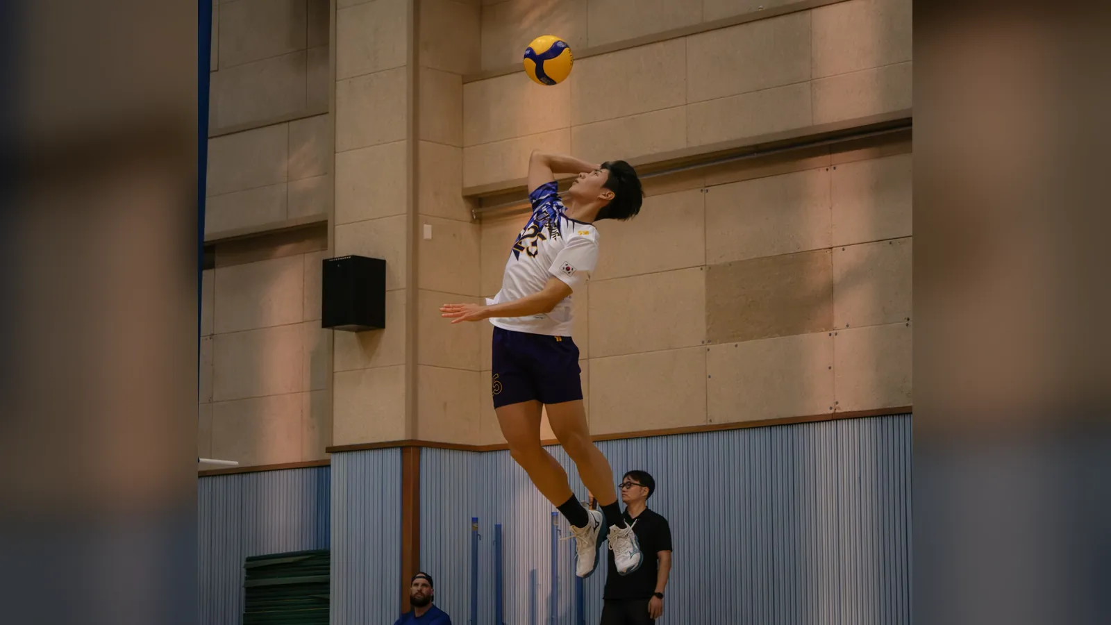Jugador de voleibol en el aire golpeando un saque en salto